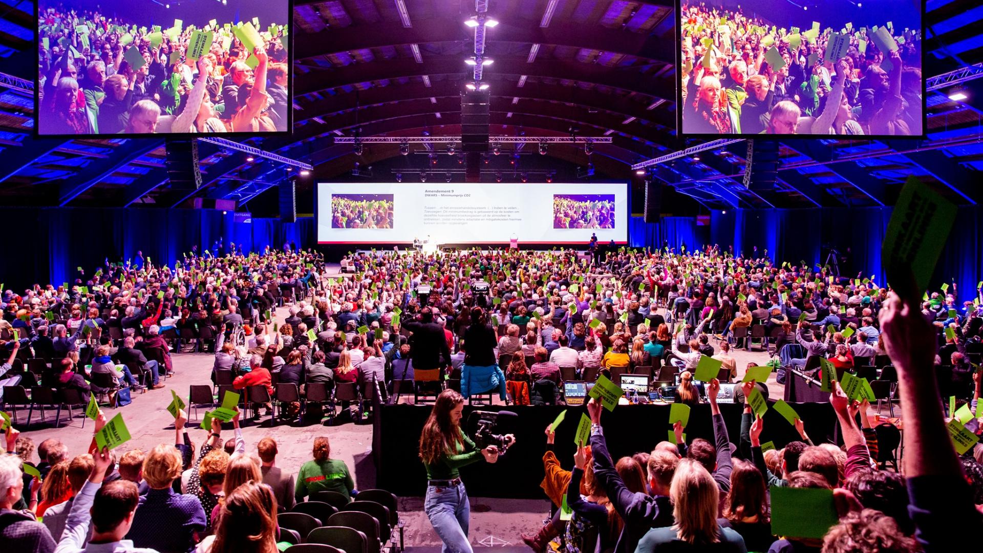 Groene stemkaarten in de lucht tijdens een GroenLinks-congres
